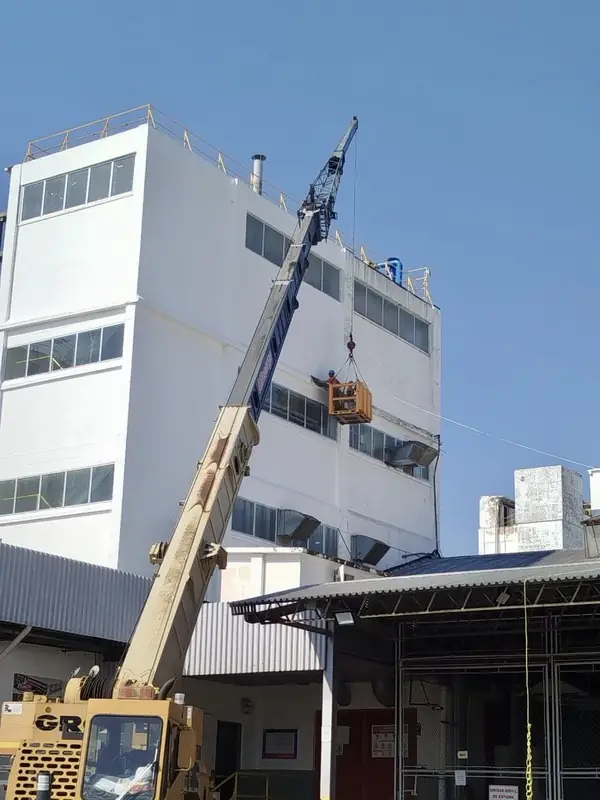 Grúa telescópica izando carga junto a una planta industrial