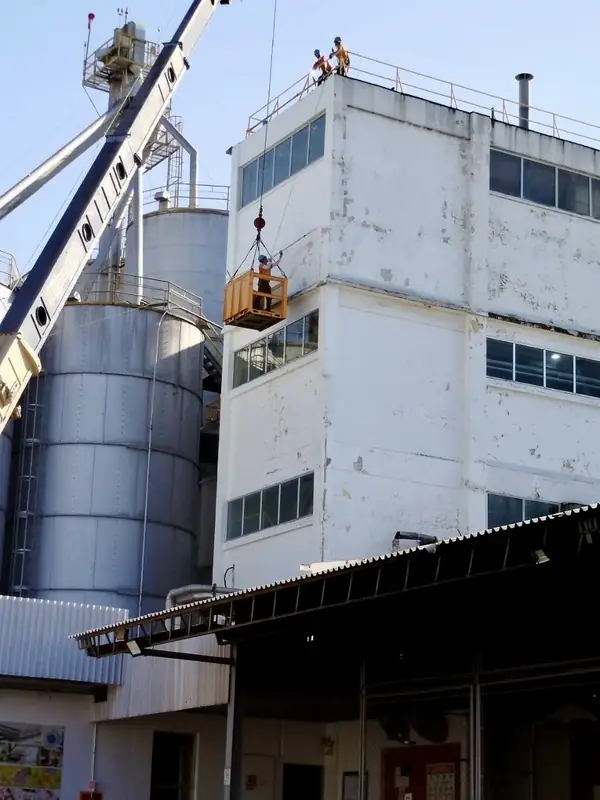 Izaje de equipo junto a silos y fachada de planta industrial