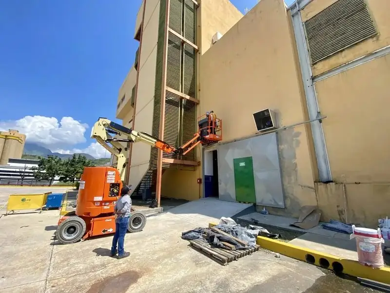 Brazo articulado interviniendo la fachada de un edificio industrial
